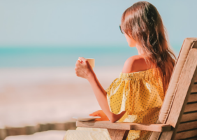 Woman sitting on the beach drinking a cup of tea