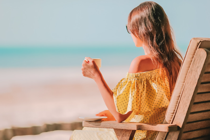 Woman sitting on the beach drinking a cup of tea