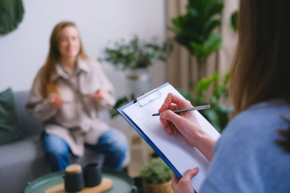 Occupational Therapist taking notes talking with their client