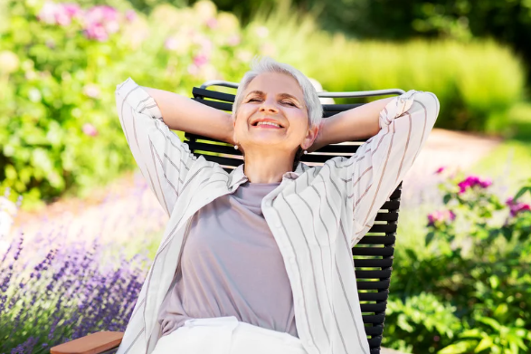 Elderly Woman sitting in the garden, enjoying the summer