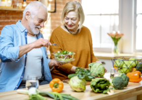 elderly couple preparing a salad in the kitchen