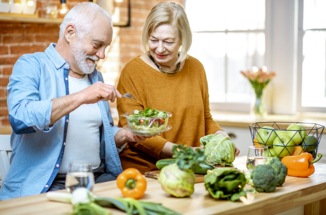 elderly couple preparing a salad in the kitchen