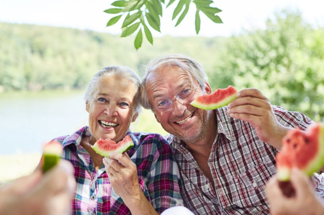 Eldrly couple eating watermelon in the sun