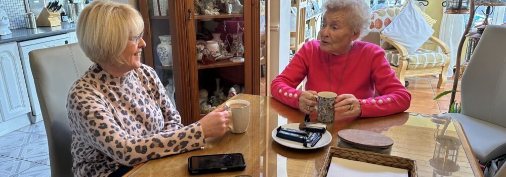 Daughter and mother enjoying a cup of tea together at home