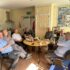Group of elderly men sitting around a table in the Men's Shed drinking tea and eating cake