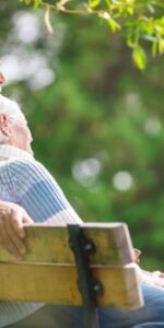 Elderly couple sitting on a park bench on a warm summers day
