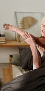 Elderly woman in bed and doing her morning stretches