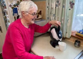 Elderly woman pouring the Uccello Kettle to make a cup of tea in her kitchen