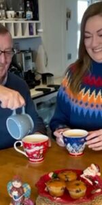 Elderly Father and Daughter sharing a cup of tea together in festive Christmas clothes