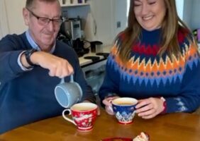 Elderly Father and Daughter sharing a cup of tea together in festive Christmas clothes