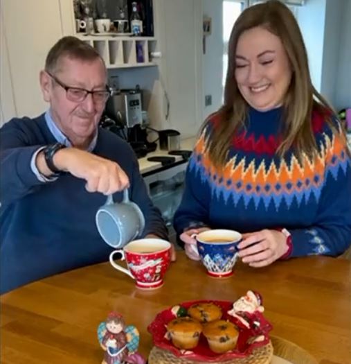 Elderly Father and Daughter sharing a cup of tea together in festive Christmas clothes