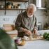 Elderly man living with arthritis cooking in the kitchen